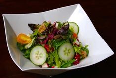 a salad with cucumbers and other vegetables in a white bowl