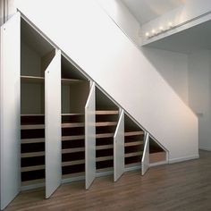 an empty room with some shelves under the stairs