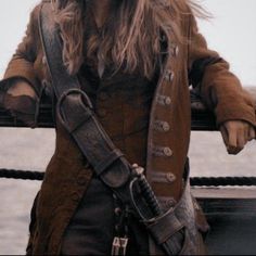 a woman dressed in pirate clothing standing on the deck of a ship