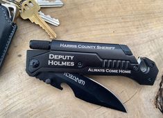 two knives are sitting next to each other on a wooden table with keys in the background