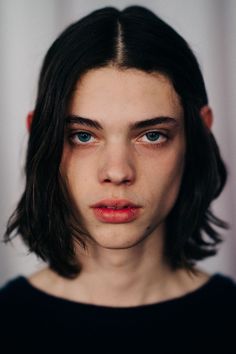 a woman with long hair and blue eyes looks at the camera while wearing a black shirt