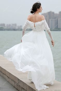 a woman in a white dress is walking along the water