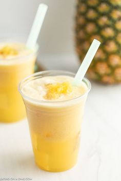 two glasses filled with drinks next to a pineapple