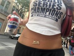 a woman holding a can of pepsi in her right hand and wearing a shirt that says pepsi world series champs new york yankees