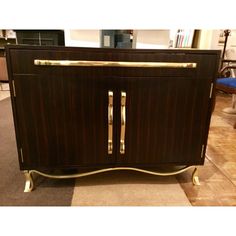 a brown cabinet with gold handles and some blue chairs in the backround behind it