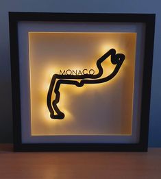 a framed art piece with the word monaco on it and a race track in black frame