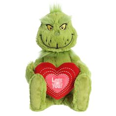 a green stuffed creature holding a red heart