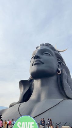 a large statue that is next to a sign with the words save earth on it