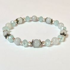 This genuine Aquamarine bracelet is 8" It is created with 8mm natural Aquamarine beads which are selected to match as best possible. To add a little sparkle are glass crystal faceted beads and silver filigree end caps.  Aquamarine is a stone of courage with calming energy to reduce life's stress and bring quiet to the mind.  Helps you connect with your inner-self and intuition. 🌹 Each piece of jewelry will come to you with the name of your stone and a brief description of the healing energy it Spiritual Silver Jade Beaded Bracelets, Spiritual Silver Beaded Jade Bracelets, Silver Jade Beaded Bracelets With Gemstones, Silver Jade Beaded Bracelets With Gemstone Beads, Silver Jade Beaded Bracelets With Round Beads, Silver Beaded Bracelets For Healing, Healing Silver Beaded Bracelets With Faceted Beads, Silver Hypoallergenic Stretch Bracelet, Silver Hypoallergenic Stretch Bracelet For Healing