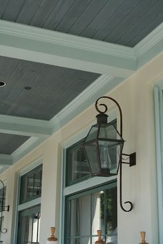 a lamp hanging from the side of a building next to an open door and windows