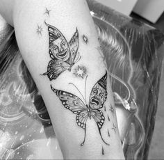 a black and white photo of a woman's arm with two butterflies on it