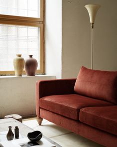 a living room with a red couch and two vases on the windows sill