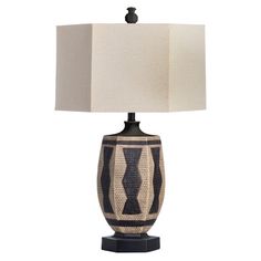 a table lamp with a black and white striped design on the base, next to a beige linen shade