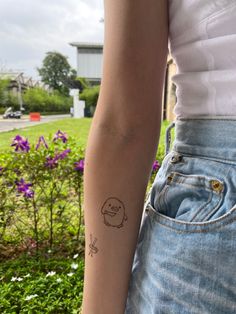 a woman's arm with a tattoo on it in front of some purple flowers