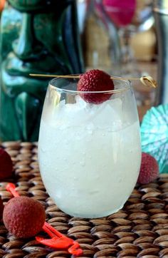 a glass filled with ice and raspberries on top of a wicker table