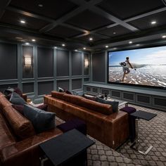 a home theater with two couches and a large screen on the wall above it