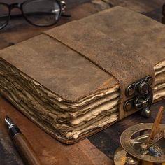 an old book sitting on top of a wooden table next to a pair of glasses