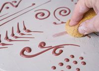 a person is using a sponge to paint the design on a piece of art paper