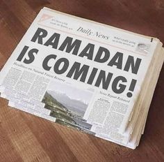 a newspaper with the words ramadan is coming on it sitting on a wooden table