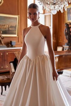 a woman in a white dress standing next to a chandelier