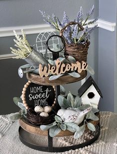 a welcome sign is sitting on top of a birdhouse with some plants in it