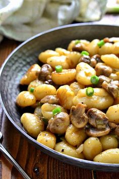 a bowl filled with mushrooms and peas on top of a wooden table