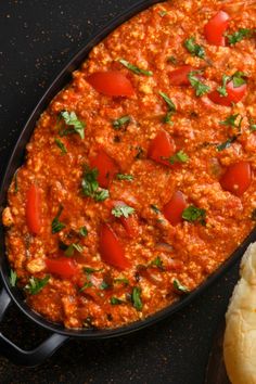 a black pan filled with food next to bread