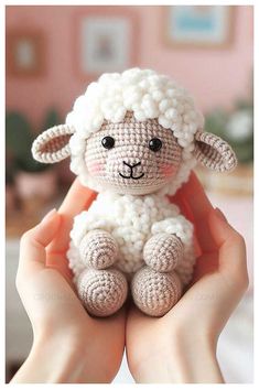 a crocheted sheep sitting in someone's hands