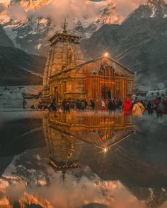 a group of people standing in front of a building with lights on it and mountains in the background