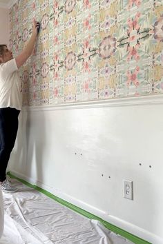 a woman is painting a wall with flowers on it