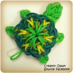 a close up of a green and yellow turtle brooch on a white surface,