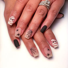 a woman's hands with halloween nail art on their nails and spider webs