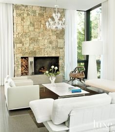 a living room filled with furniture and a fire place in front of a stone wall