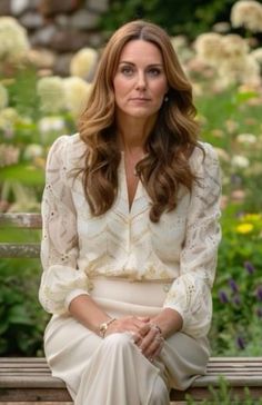 a woman sitting on top of a wooden bench next to flowers and trees in the background