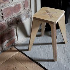 a small wooden stool sitting next to a brick wall and floor in front of a fire place