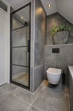 a bathroom with a toilet, shower and planter in the corner on the wall