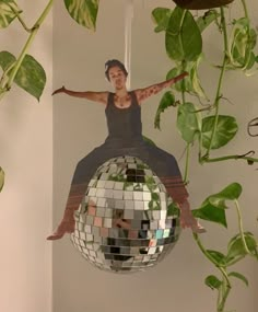 a woman hanging from a plant with a disco ball in front of her