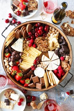 an assortment of cheeses, crackers and berries in a wooden bowl on a table