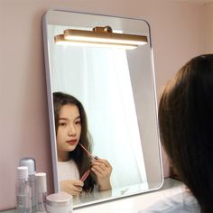 a woman is brushing her hair in front of a mirror while she brushes her teeth