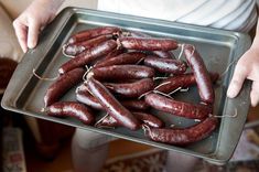 a person holding a tray full of sausages