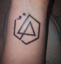 a black and white photo of a tattoo on someone's wrist that has a triangle in the middle