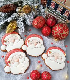 decorated cookies with santa claus faces on them and christmas decorations in the back ground next to pine cones