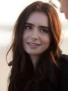 a close up of a person with long hair and blue eyes looking at the camera