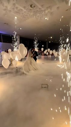 a bride and groom are standing in the middle of a room with balloons floating around