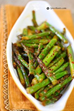 asparagus with sesame seeds and seasoning in a white bowl on a wooden table