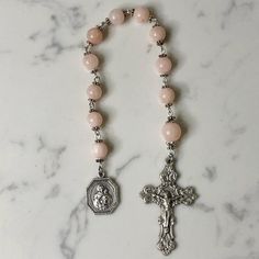 Handmade traditional Catholic single decade tenner rosary using light pink dyed jade smooth round stone beads. Antique silver daisy bead caps on every bead with additional flower bead caps on Our Father bead. Antique silver Our Lady of Schoenstatt Medal with Ornate Fleur-de-Lis Crucifix. Hail Mary beads are 8mm with the Our Father bead being 10mm. Designed to be used and/or displayed. Measures about 10" long. This rosary would make a beautiful gift for a baby shower, Baptism, First Communion, Reconciliation, Confirmation or any other special event or occasion. Comes in a beautiful black velvet pouch. I ship same or next business day. All of my rosaries are one of a kind and are my own personal creation. Photos are a part of the description-you will receive the exact rosary pictured. Please Pink Rosary Beads, Spiritual Pink Spacer Beads, Pink Spiritual Faceted Beads, Adjustable Rosary With Faceted Round Beads, Spiritual Hand-strung Pink Beads, Spiritual Pink Hand-strung Beads, Spiritual Rosary With Spacer Beads, Pink Hand-strung Spiritual Rosary Bracelet, Pink Spiritual Rosary Bracelet With 8mm Beads