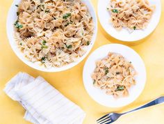 two white plates with pasta and broccoli on them next to a silver fork