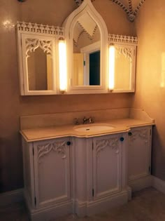 a bathroom with a sink, mirror and lights on the wall above it's cabinets