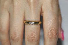 a close up of a person's hand with a diamond ring on their finger