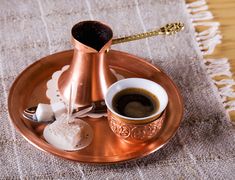 a cup of coffee sitting on top of a saucer next to an empty spoon